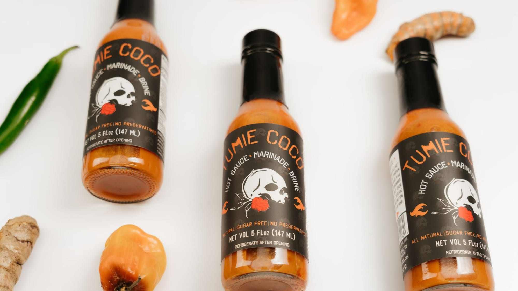 Tumie Coco hot sauce bottles with fresh chilies and turmeric